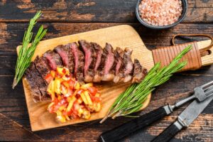 Grilled top sirloin cap or picanha steak on a cutting board with herbs.